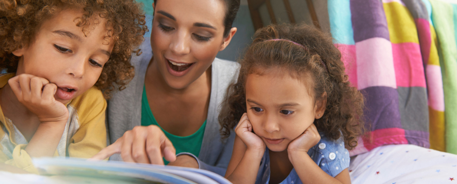 Siblings reading together on a bed with their mom